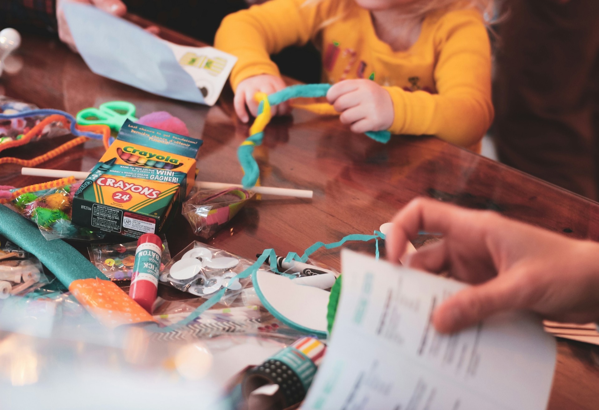 young girl sitting at a table with lots of craft supplies