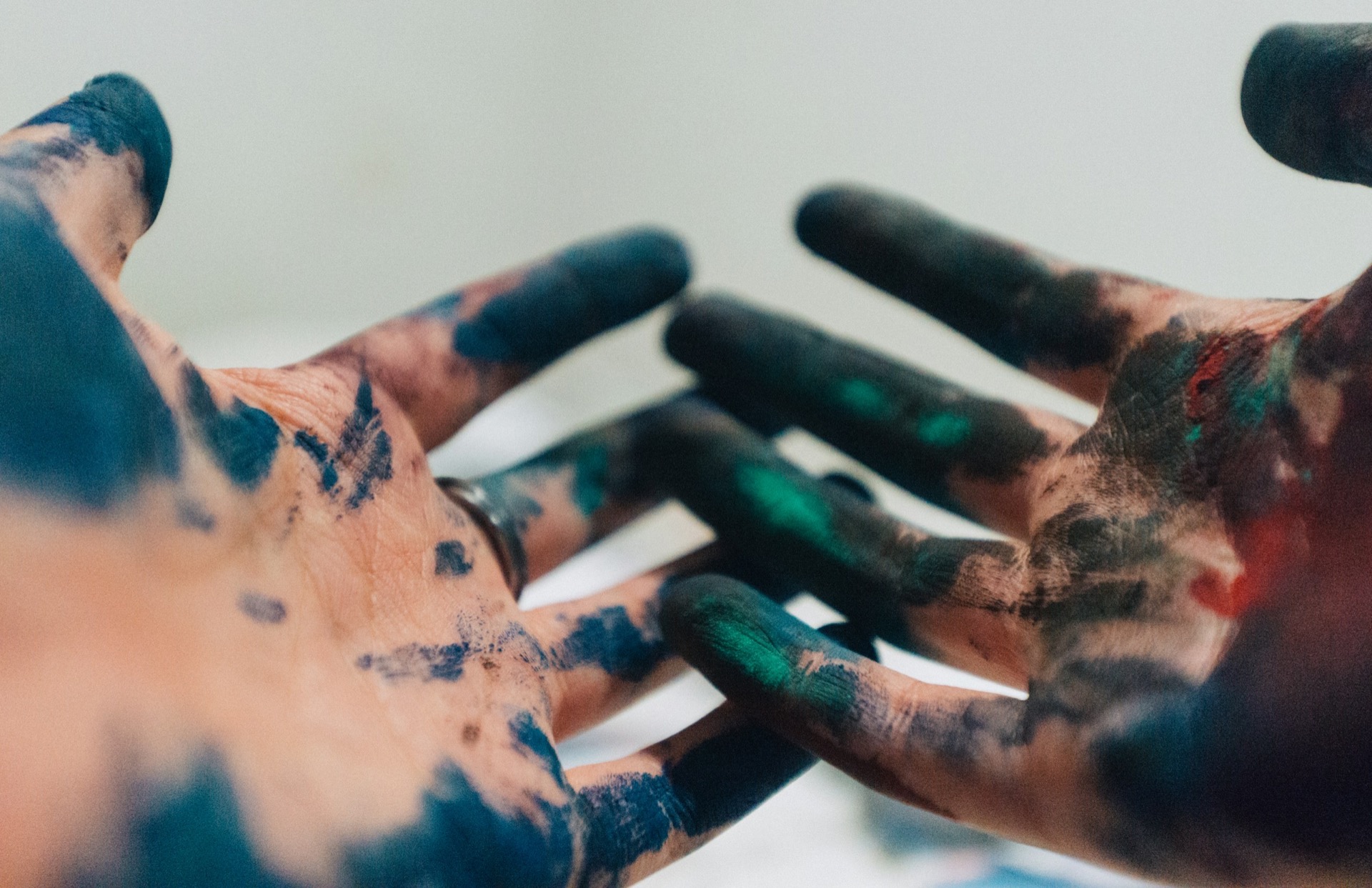 child's hand covered in green and blue paint during open-ended art play